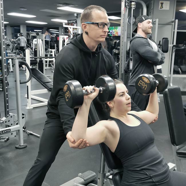 Coach Donovan training a personal training client in the gym with dumbbells